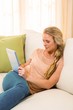 © WavebreakmediaMicro - Pretty blonde using tablet sitting on the couch