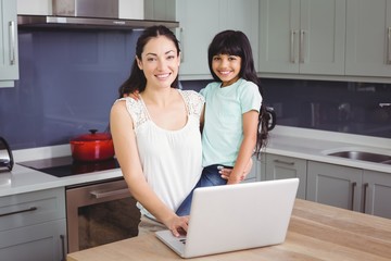 Wall Mural - Portrait of smiling mother and daughter using laptop