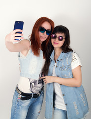 beauty hipster girls with a headphones, make selfie on a phone. teenagers grimace