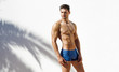 Muscular man wearing blue beach shorts and posing