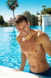 Photo of handsome smiling man in swimming pool in summer scenery