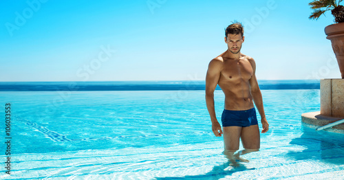 Cuadros en Lienzo Muscular man in the swimming pool posing in summer scenery