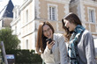 © Monet - Two women are laughing while looking at the smartphone outside