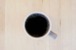 © irisphotoimages - Black coffee in cup on blond wood tabletop. Top view.