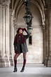 © ginkgofoto - Beautiful young woman with coat and stockings standing in arcades and looking up