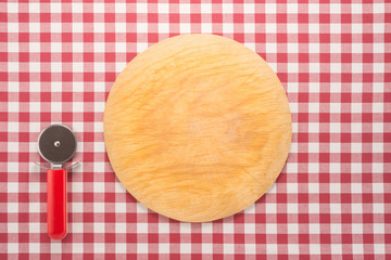 Wall Mural -  Pizza cutting board and round knife on cotton tablecloth 