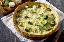 Open pie quiche Lauren with broccoli and cheese on a dark wooden