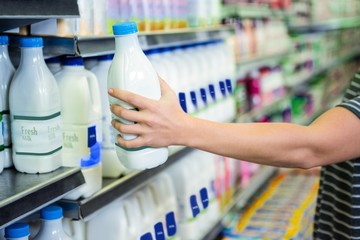 Womans hand holding milk bottle