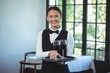 © WavebreakMediaMicro - Smiling waitress holding a tray with glasses of red wine
