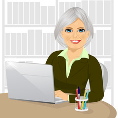 Wall Mural - successful mature businesswoman working typing on her laptop at office