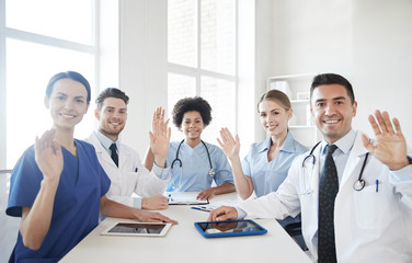 Poster - happy doctors meeting and waving hands at hospital