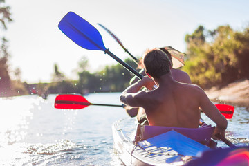 Young people are kayaking on a river in beautiful nature. Summer sunny day