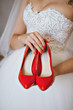 Photograph of a unrecognizable bride holding wedding red shoes