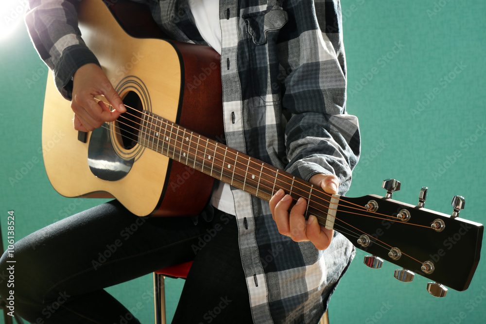 Musician plays guitar on blue background, close up