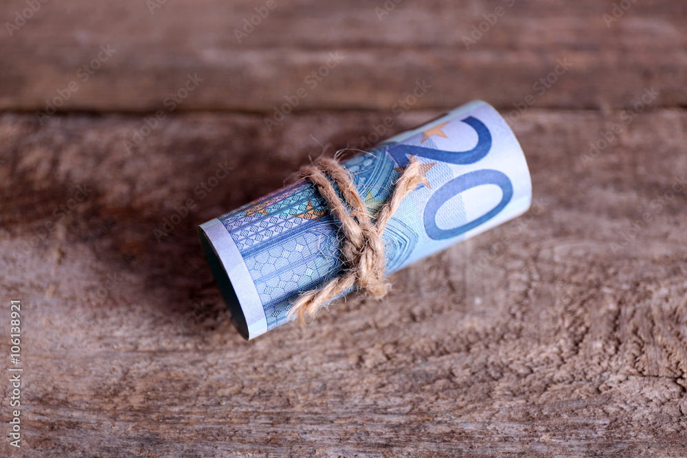 Roll of Euro banknotes on wooden background