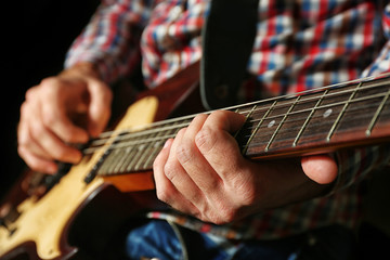 Wall Mural - Young man playing on electric guitar close up