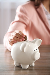 Sticker - Woman putting coin into piggy bank at the table