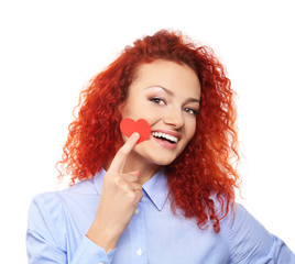 Poster - Red-haired young woman holding paper red heart near cheek, isolated on white