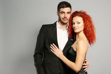 Poster - Happy young couple in black dress and suit embracing on grey background