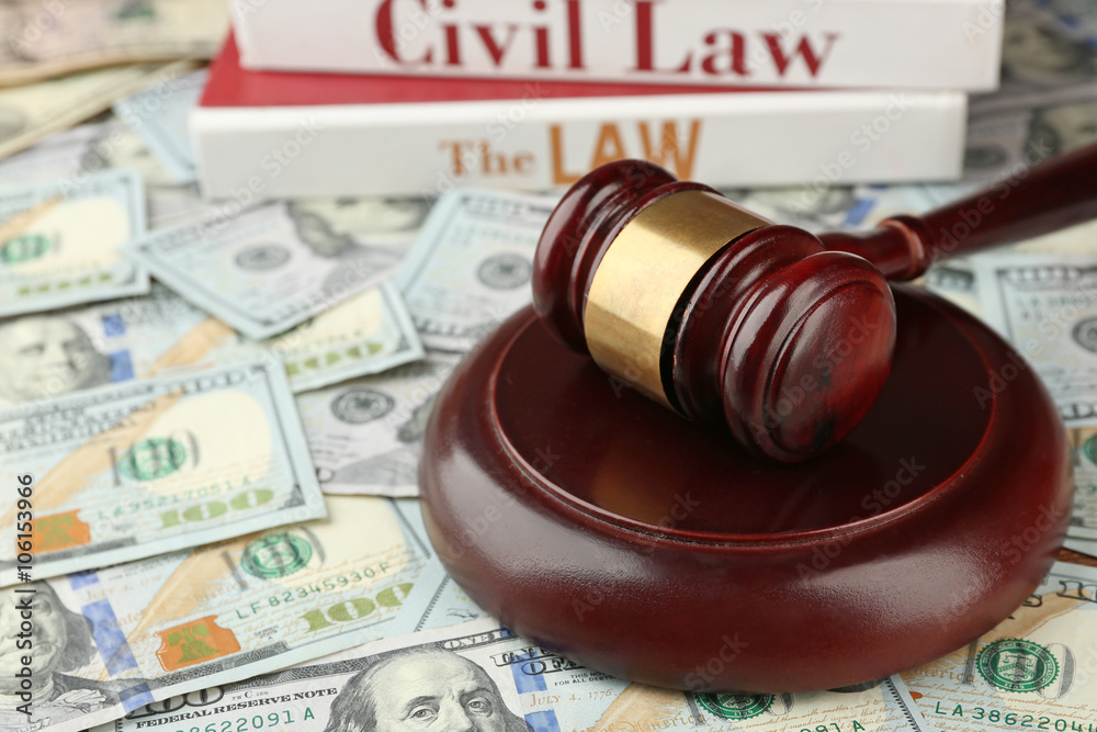 Law gavel with books on dollars background, closeup