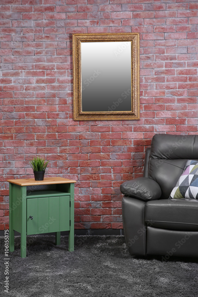 Brown leather armchair and green small table against brick wall background
