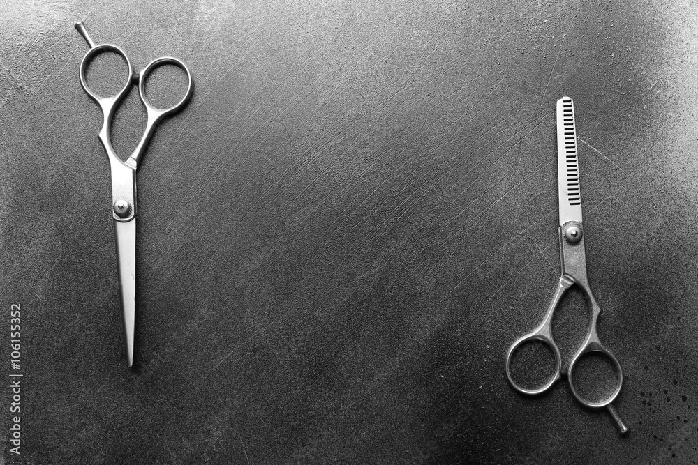 Professional metal scissors lying in two different positions on the grey surface with copy space, top view