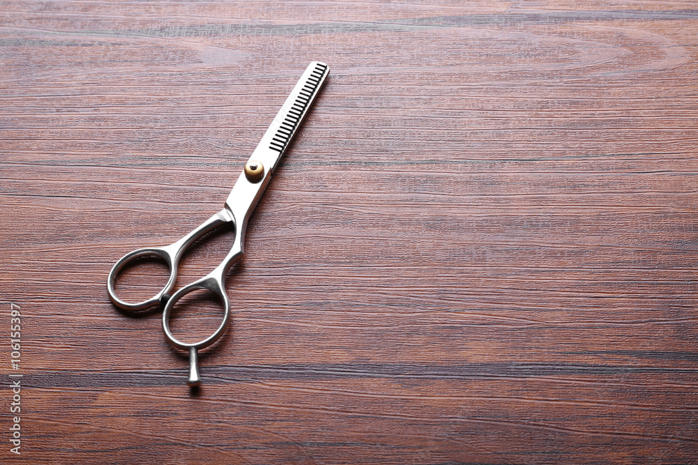 Professional metal scissors lying on the wooden table, close up