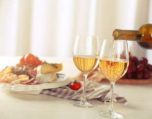 Wall Mural - Pouring white wine into glass and food on table indoors