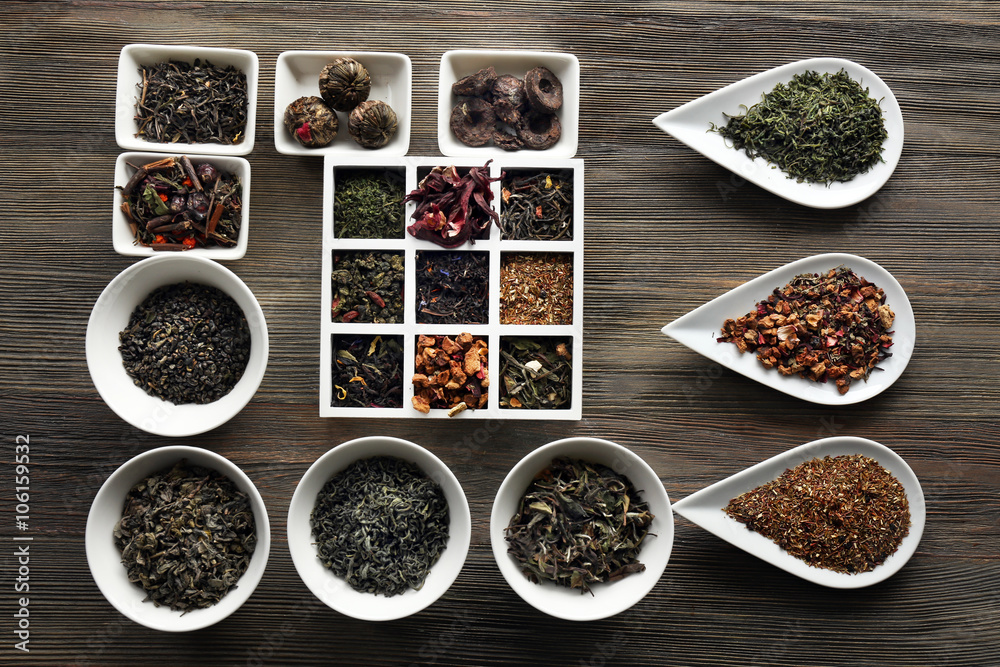 Tea concept. Different kinds of tea in ceramic bowls on wooden background