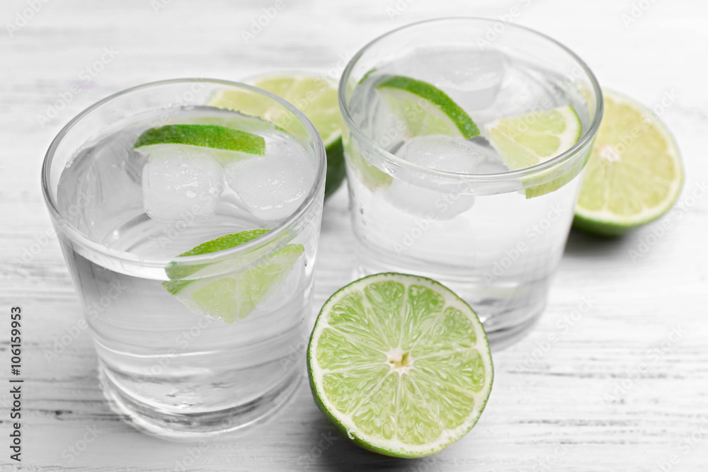 Fresh cocktails with ice and lime on white wooden table background