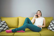 © bokan - Beautiful young woman talking on telephone in her living room