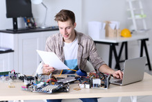 Young Man Repairing Computer Hardware And Using Laptop In Service Center