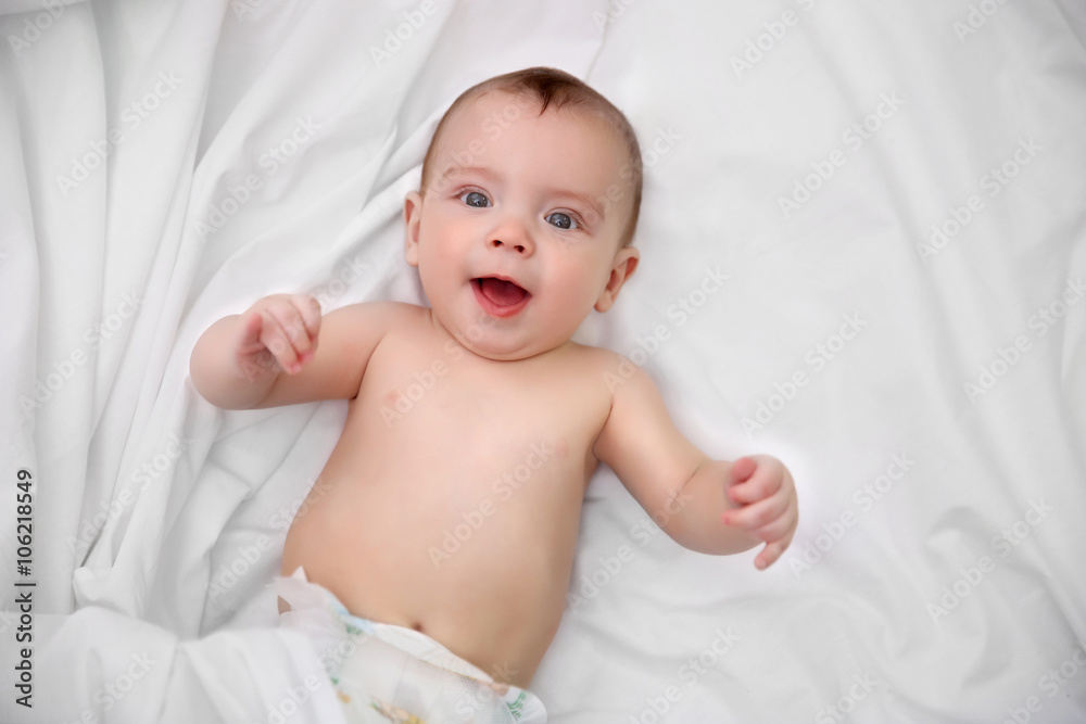 Naked adorable baby lying on soft bed, close up