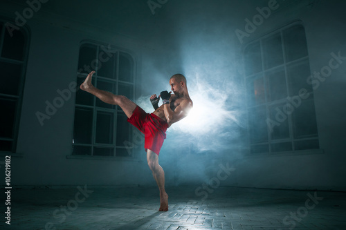 Cuadros en Lienzo The young man kickboxing in blue smoke