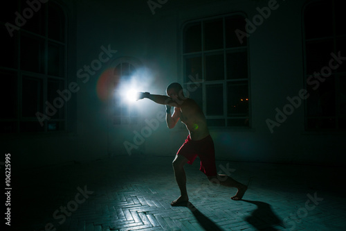 Εκτύπωση καμβά The young man kickboxing on black background
