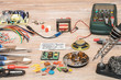© arkstart - Tools for the designing and repair of electronic devices. Soldering iron, tools, electronic components, wire, devices and multimeter on a wooden table.