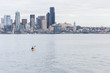 A lone kayaker paddles toward the Seattle skyline on a calm spring day.
