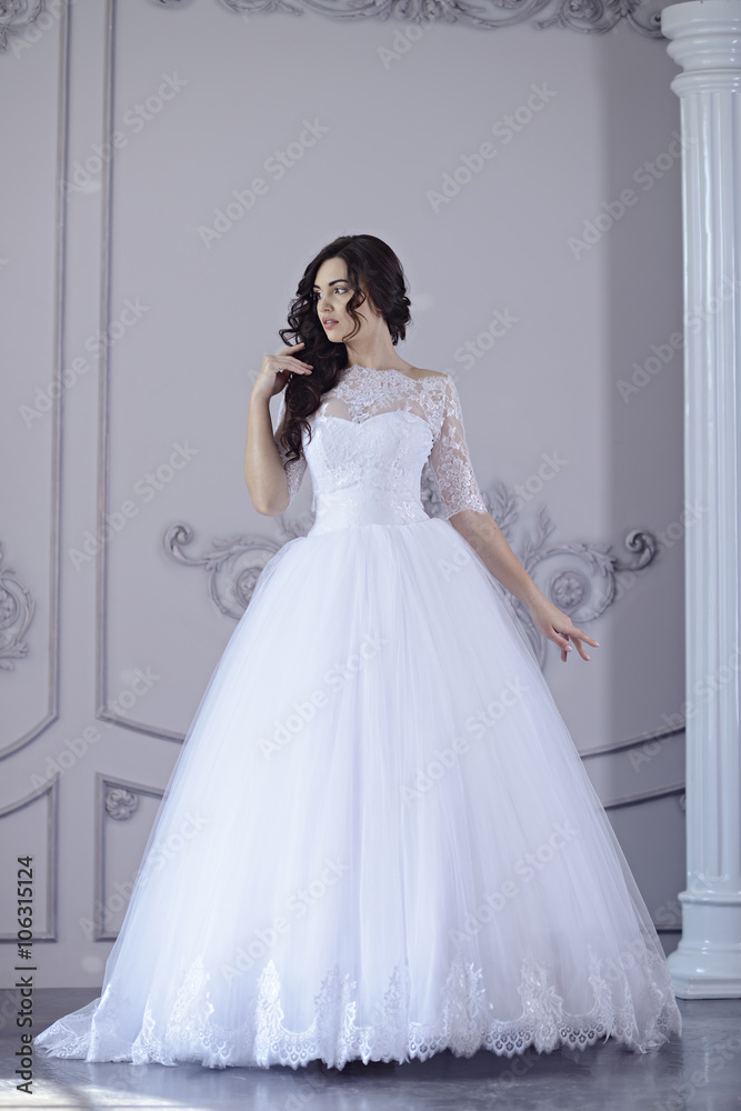 Photo Stock Beauty bride in bridal gown indoors. Beautiful model girl in a  white wedding dress. Female portrait of cute lady. Woman with hairstyle |  Adobe Stock