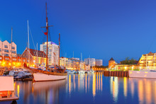 Tourist Ships In Harbor At Motlawa River And The Milk Can Gate, Brama Stagiewna At Night, Gdansk, Poland