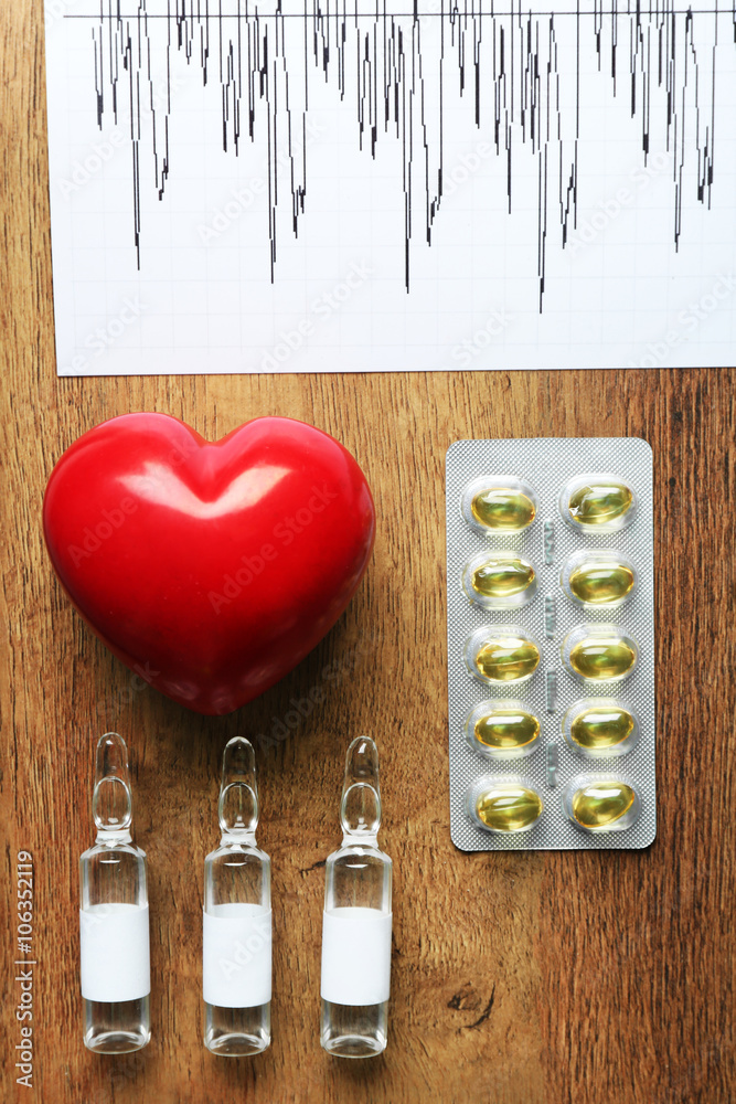 Doctor table with cardiogram, pills, capsules and red heart, top view