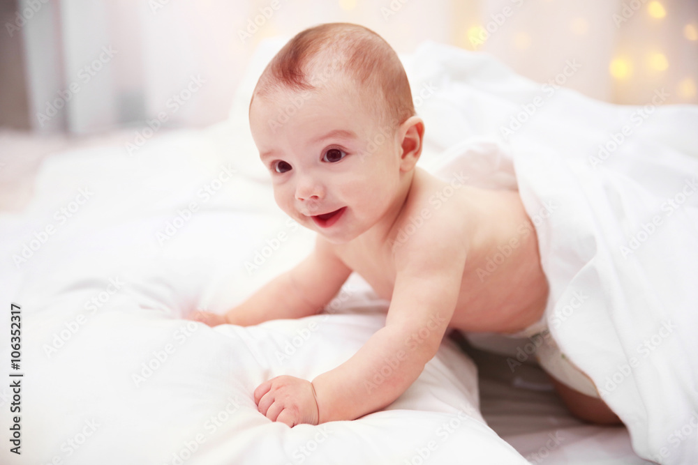 Naked adorable baby lying on soft bed, close up