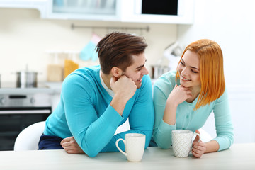 Canvas Print - Happy young couple drinking tea in the kitchen at home