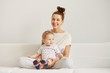 © WHstudio Leushin N - Young mother with her one years old little son dressed in pajamas are relaxing and playing in the bedroom at the weekend together, lazy morning, warm and cozy scene. Selective focus.