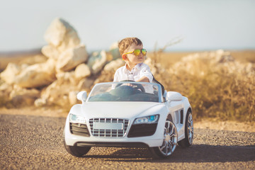 Happy little boy travel by car in summer