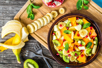 Wall Mural - fruit salad in a clay brown dish, close-up, top view