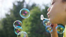 Close Shot Of Little Girl Blowing Bubbles Outside, In Slow Motion