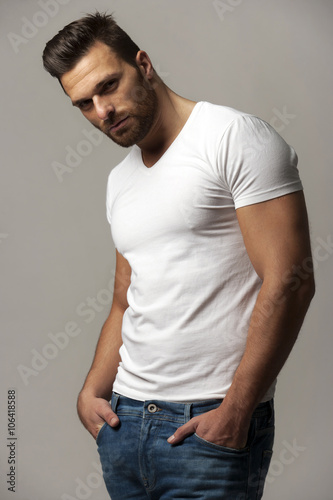 Fotografia Handsome young man in white t shirt and jeans on gray background