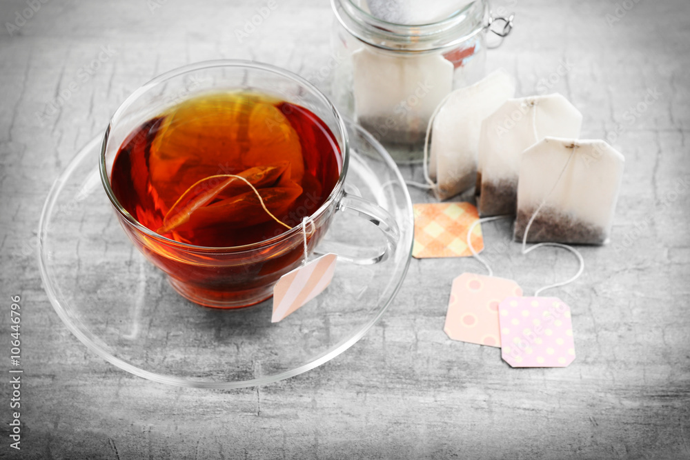 Cup of tea with tea bags on grey background