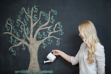 Happy blonde Business woman in front of chalk money tree drawing