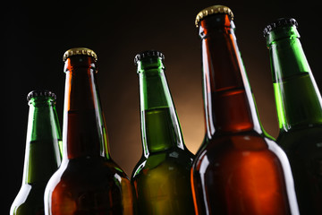 Wall Mural - Green and brown glass bottles of beer on dark lighted background, close up
